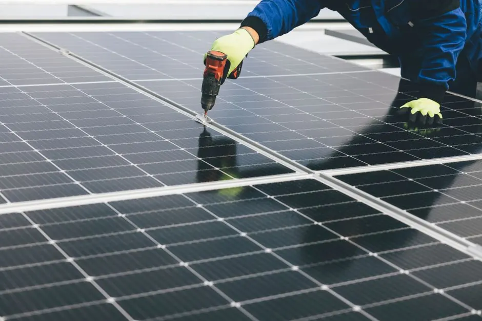 A technician uses a power tool to install solar panels, showcasing renewable energy efforts.