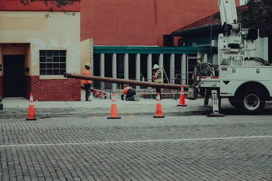Street construction site with workers and equipment in an urban setting. Ideal for industry-themed projects.